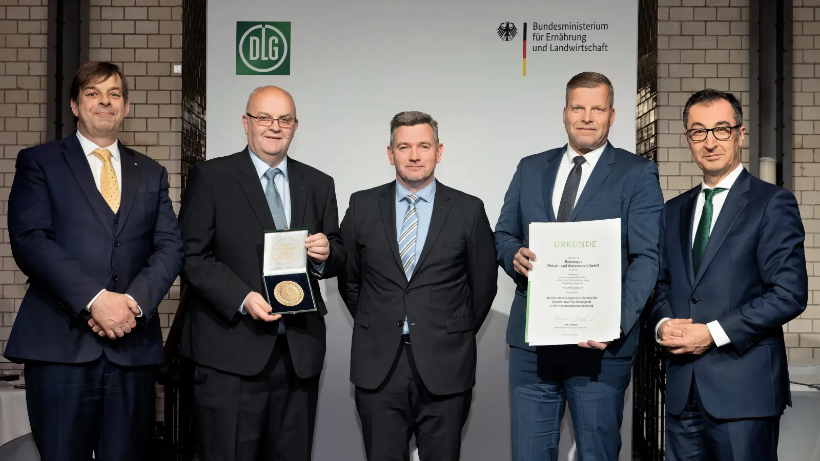 Bundesminister Cem Özdemir (rechts) überreicht Urkunde und Medaille gemeinsam mit DLG-Präsident Hubertus Paetow (links) an Klaus Jeinsen (Geschäftsführer Bauerngut), Olaf Pöhl (Produktionsleiter Bückeburg) und Andreas Seidel (Prokurist). (Foto: DLG / Christian Lietzmann)