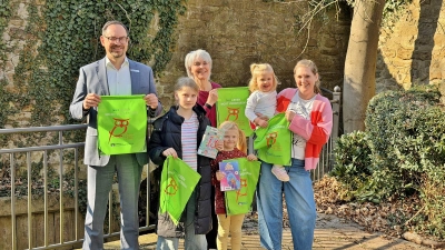 Mama Johanna weiß, dass Moira, Geesje und Leevke wahre Leseratten sind und holt sich zusammen mit ihren Kindern die grünen Lesebeutel in der Stadtbücherei ab, die von Manuel Wiegand von der Volksbank in Schaumburg und Nienburg eG an Büchereileiterin Bärbel Hanauske übergeben wurden. (Foto: ste)