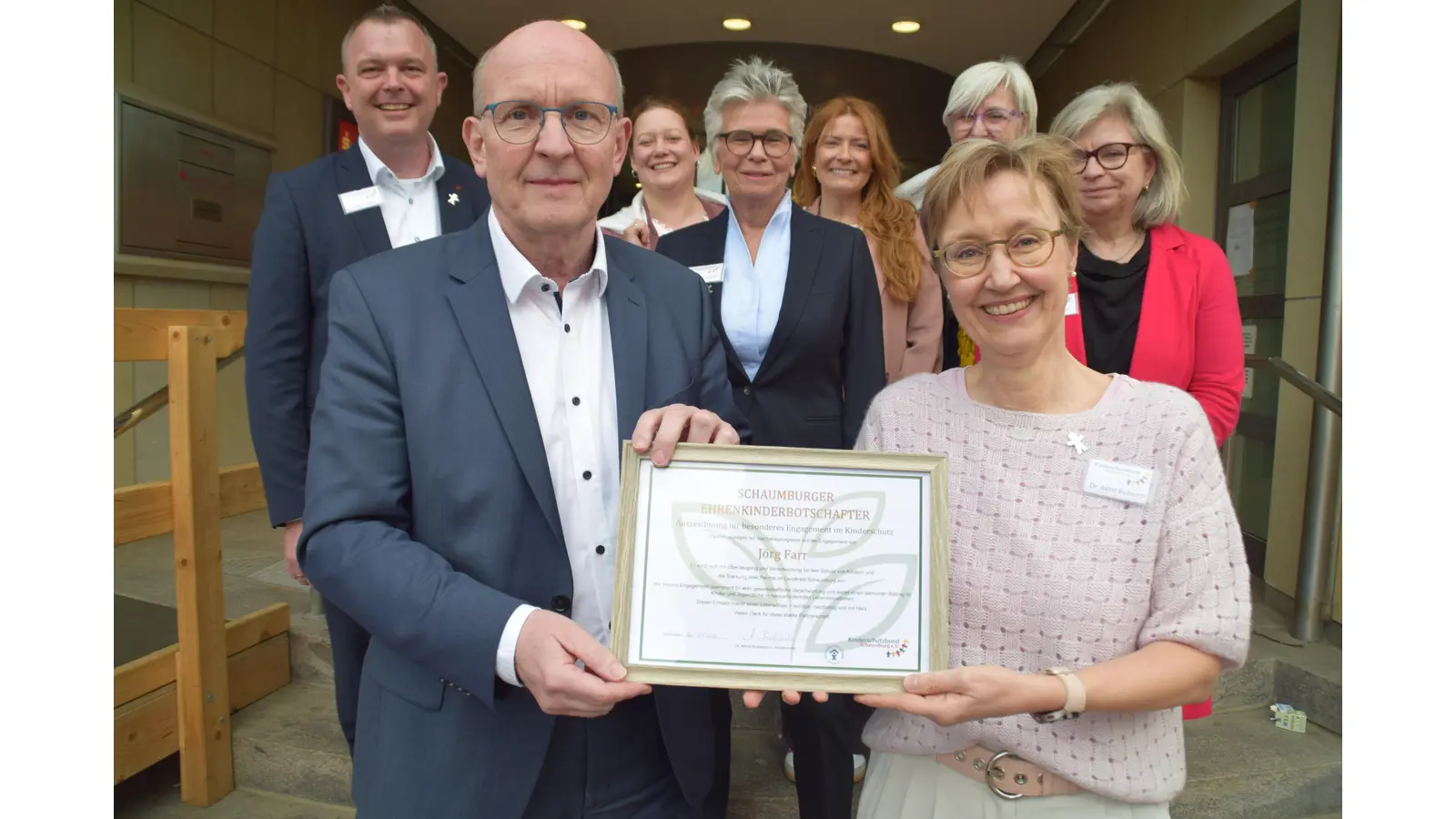 Landrat Jörg Farr (li. vorn) erhält die erste Anerkennung als Ehrenkinderbotschafter für besonderes Engagement für den Kinderschutz aus den Händen von Astrid Budwach. (Foto: ab)