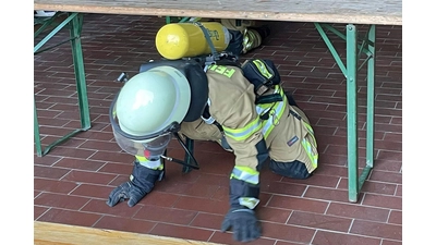 Eine Feuerwehrfrau klettert unter einem Tisch durch. (Foto: Lisa Scheibe und Daniel Bulmahn)