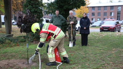 Jürgen Pickert von der Fliegerhorst-Feuerwehr wässert den Ahorn: Den Baum haben Markus Knoll (v.li.), Mirko Neuhaus und Carry Leriche gepflanzt. (Foto: gi)