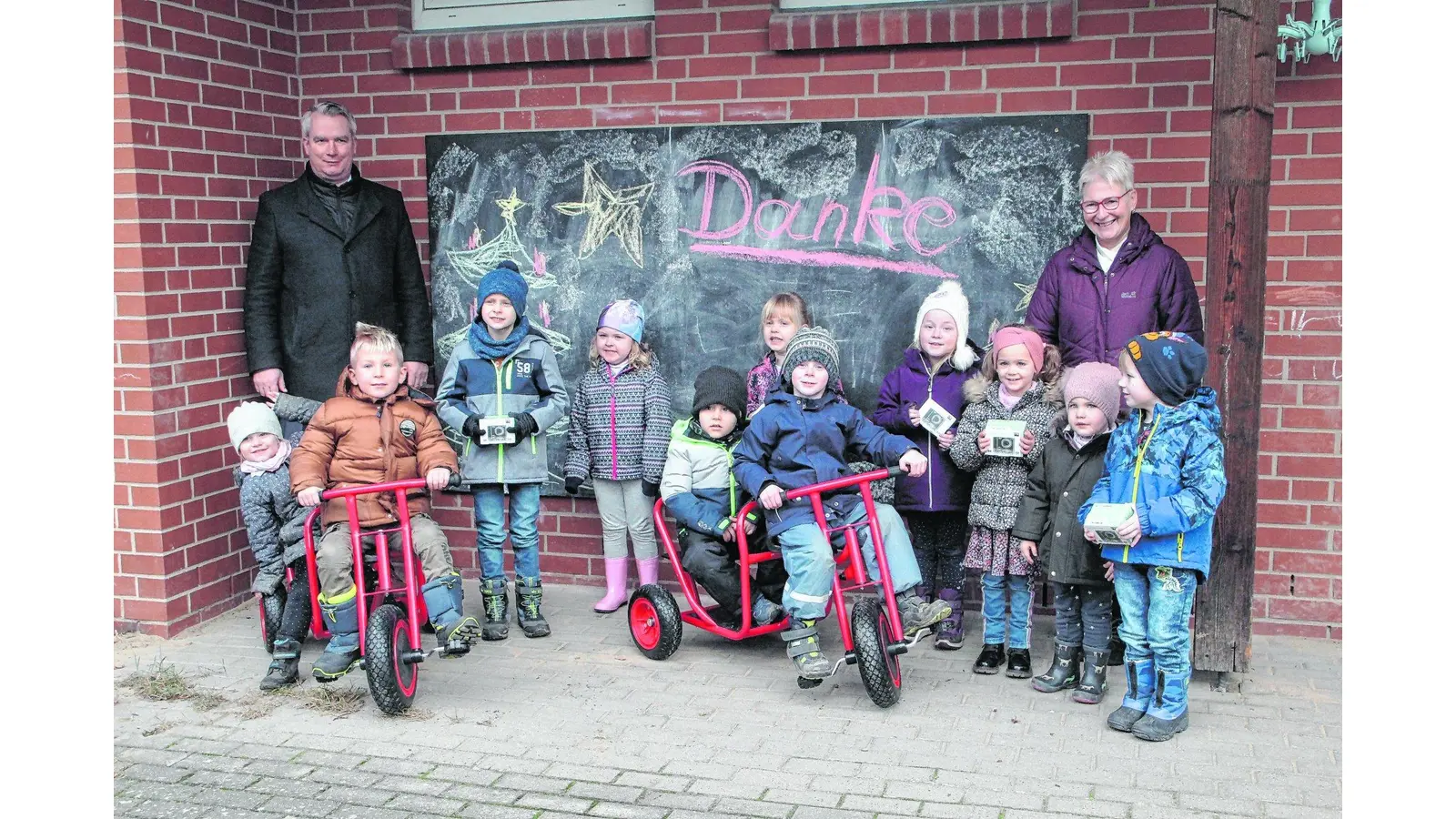 Alexander Zuschlag und Kita-Leiterin Sabine Hage freuen sich mit den Kindern über die Kindertaxis und Digitalkameras für die Gruppen, gesponsert von der Volksbank in Schaumburg. (Foto: red)