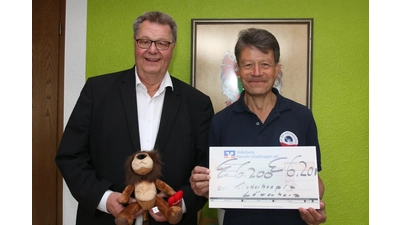 Bernd Gerberding (li.) übergibt einen symbolischen Spendenscheck über 6.200 Euro an Martin Sellmann, Vertreter des „Kinderhospiz Löwenherz“, und erhält dafür das Maskottchen der Einrichtung.  (Foto: bb)
