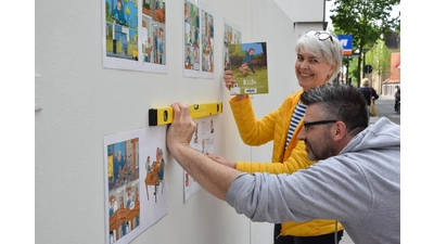 Bärbel Hanauske und André Klee tackern den Comic „Kiste“ an den Plattenzaun an der Klosterstraße. (Foto: ste)