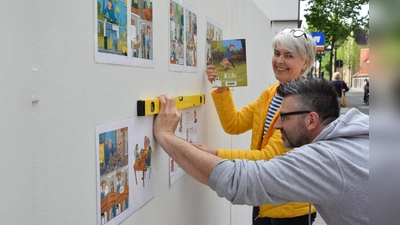 Bärbel Hanauske und André Klee tackern den Comic „Kiste“ an den Plattenzaun an der Klosterstraße. (Foto: ste)