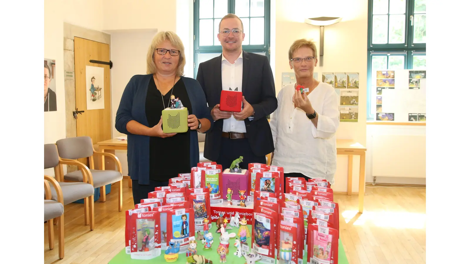 Cornelia Reuter (li.), Leiterin der Stadtbücherei Stadthagen, Christopher Held von der Volksbank Hameln-Stadthagen und Ute Schaper von den Bücherfreunden Stadthagen mit den 70 neuen „Tonies“.