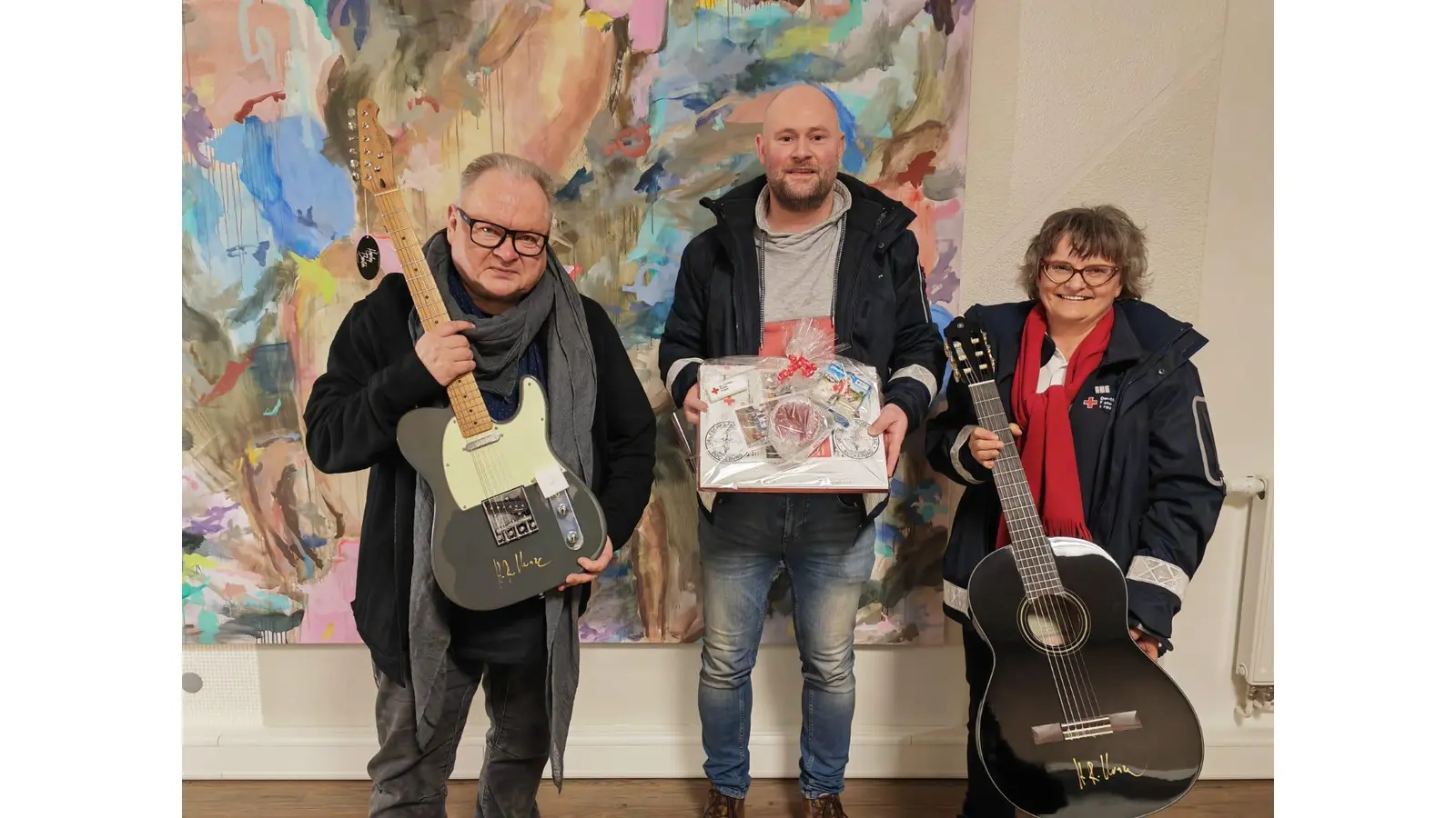 Musiker Heinz Rudolf Kunze (v.li.), DRK-Ortsvereinsvorsitzender Sven Lampe und Ellen Heller mit den jeweiligen Gitarren und Präsent. (Foto: pr)