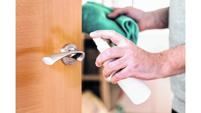 hand of a man sanitizing a doorknob with disinfectant spray and a cloth, hygiene concept and protection against viruses and bacteria (Foto: mk)