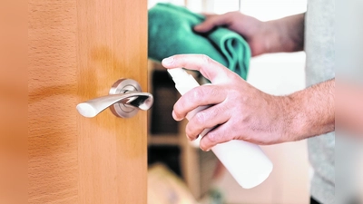 hand of a man sanitizing a doorknob with disinfectant spray and a cloth, hygiene concept and protection against viruses and bacteria (Foto: mk)