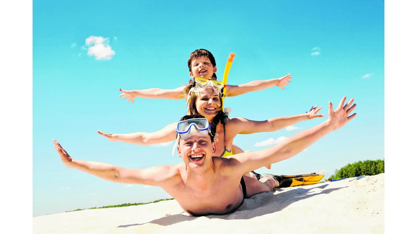 Portrait of cheerful couple and their son lying on sand and looking at camera (Foto: red)