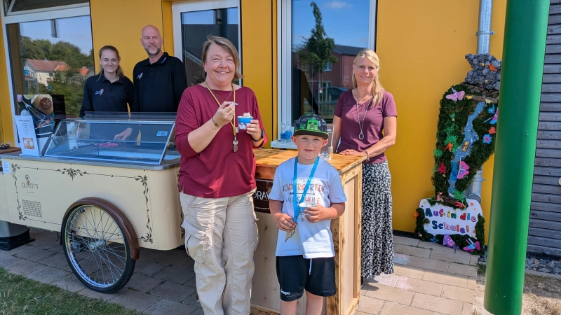 Das Team des Volksbank-Eismobils sorgt für strahlende Gesichter: Ilona Grondstein (mitte), Linus und Volksbank-Mitarbeiterin Sonja Springinsgut (rechts) lassen sich die süße Überraschung schmecken. (Foto: privat)
