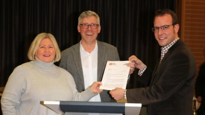 Christiane Schweer (li.) und Martin Ehlerding (re.) überreichen Carsten Piellusch vor dem neuen schicken Rednerpult den Antrag zur Verlängerung der Parkzeit. (Foto: gi)