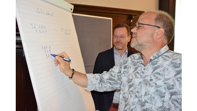 Stadtjurist Jan Boße lässt sich von Helge Krüger bei der Verleihung der Ehrenamtskarte erläutern, wie er anhand von Rechenbeispielen seinen Klienten bei der Bearbeitung von Steuererklärungen hilft.  (Foto: ste)